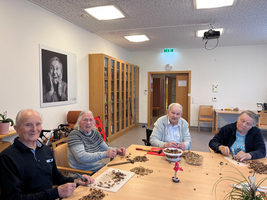 Vier ältere Menschen sitzen an einem Tisch und knacken Nüsse.