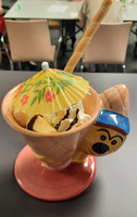 Eine bunte Eistasse mit Obst, Sahne und einem kleinen Regenschirm.
