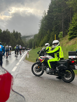 Polizisten in Neonjacken beobachten Radfahrer auf einer regnerischen Landstraße.