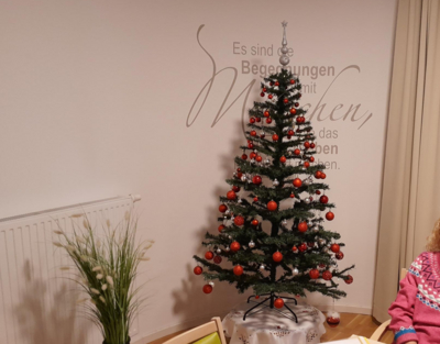 ein Christbaum mit roten Kugeln steht vor einer Wand in einem Wohnzimmer, Weihnachtsfeier, Senioren-WGs
