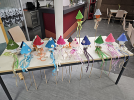 Bunte, selbstgemachte Hüte stehen auf einem Tisch, dekoriert mit Schleifen.