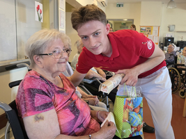 Die ältere Frau erhält ein Geschenk von einem jungen Mann in einem Pflegeheim.