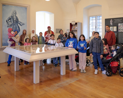 eine Gruppe aus Kindern und Erwachsenen steht in einem Raum von Schloss Hof, auf einer Wand ist ein Bild von Napoleon, Generationenausflug