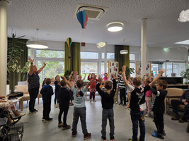 Kinder stehen mit erhobenen Händen im Kreis und tanzen zusammen.