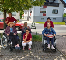 Gruppierung von Senioren in Rollstühlen mit Betreuern im Freien.