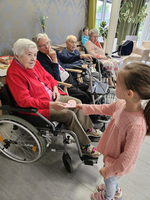 Ein Mädchen überreicht einer älteren Dame eine Karte in einem Pflegeheim.
