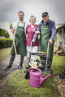 Drei Personen im Garten, mit einem Rollator und einer Gießkanne.