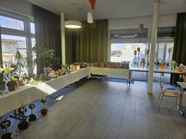 Raum mit gedeckten Tischen voller kunstvoll dekorierter Ostereier und Bastelarbeiten.