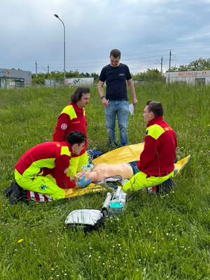 Drei Sanitäter führen mithilfe einer Übungspuppe Übungen auf einer Wiese durch.