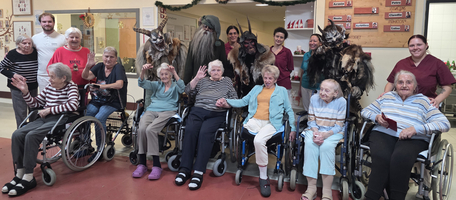 Gruppenfoto mit Senioren in Rollstühlen und verkleideten Personen in einer Einrichtung.