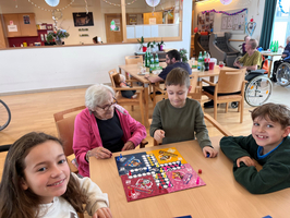 Vier Personen spielen gemeinsam ein Brettspiel in einem freundlichen Raum.