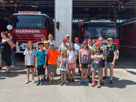 Gruppe von Kindern und Betreuern vor einem Feuerwehrhaus.