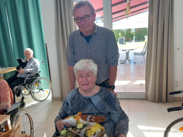 Eine ältere Frau im Rollstuhl hält einen dekorierten Osternest.