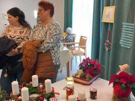 Zwei Personen betrachten weihnachtliche Dekorationen und Kerzen auf einem Tisch.