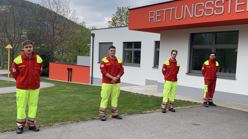 Vier Rettungskräfte stehen vor einem Gebäude mit der Aufschrift 