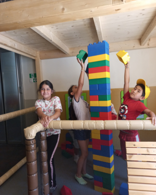 Kinder in Indoor-Spielraum, mit großen bunten Baublöcken, bauen einen Turm