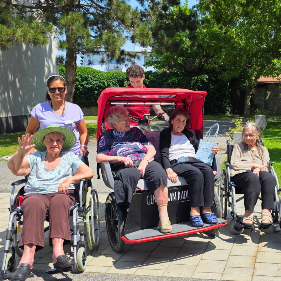 Ältere Menschen in Rollstühlen genießen einen sonnigen Tag im Freien.