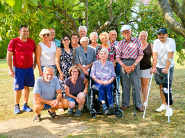 Gruppe von Menschen unterschiedlichen Alters posiert fröhlich im Freien.
