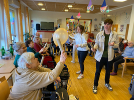 Junge Menschen animieren Senioren zu einem aktivierenden Spiel mit Luftballons.