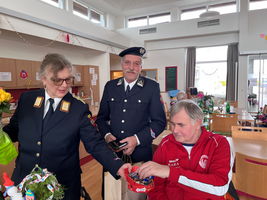 Drei Personen in Uniform teilen Geschenke in einem festlich geschmückten Raum.