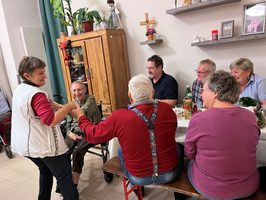 Eine Gruppe von Menschen sitzt zusammen und genießt eine gesellige Unterhaltung.