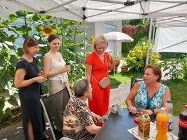Eine Gruppe von Frauen unterhält sich entspannt im Garten bei Getränken.