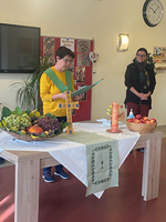 Eine Person liest vor, während Obst und eine Kerze auf dem Tisch stehen.