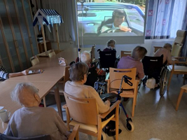 Ältere Menschen schauen gemeinsam einen Film in einem Aufenthaltsraum.