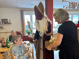 Eine ältere Frau erhält Geschenke vom Nikolaus in einem gemütlichen Raum.