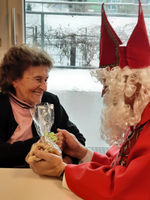 Eine Frau lächelt glücklich, während sie Geschenke von einer Person im Kostüm erhält.