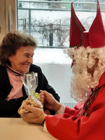 Eine Frau lächelt glücklich, während sie Geschenke von einer Person im Kostüm erhält.