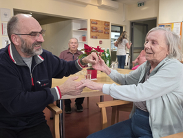 Ein lächelnder Mann und eine Frau halten sich an den Händen in einem Gemeinschaftsraum.