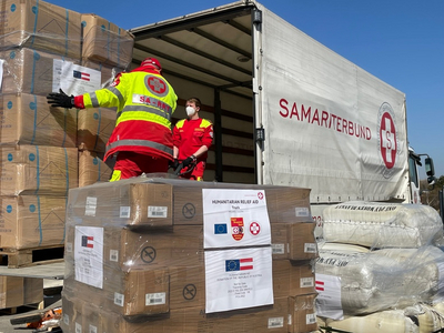 Helfer laden humanitäre Hilfsgüter in einen Lkw des Samariterbundes.