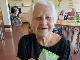 Eine ältere Frau hält stolz einen handgemachten Gegenstand in der Hand.