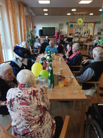 Senioren feiern gemeinsam in einem festlich dekorierten Raum mit Getränken und Snacks.