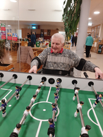 Ein älterer Mann spielt Tischfußball in einer freundlichen Gemeinschaftseinrichtung.