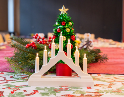 auf einem weihnachtlich gedeckten Tisch steht ein kleiner Christbaum und ein Kerzenständer mit 7 Kerzen, Weihnachtsfeier, Senioren-WGs