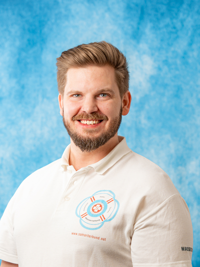 Lächelnder Mann trägt ein T-Shirt mit dem Logo des Samariterbundes.