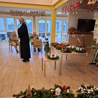 Ein Mann in Robe spricht zu älteren Menschen in einem Gemeinschaftsraum.
