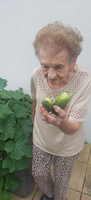 Eine ältere Frau hält zwei Gurken in der Hand.