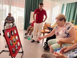 Eine ältere Frau wirft einen Ball auf ein Spielbrett während einer Gruppenaktivität.