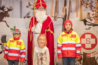 Der Nikolaus steht mit drei Kindern auf der Bühne.