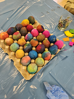 Bunte, dekorierte Eier in einem Karton auf einem blauen Tisch.
