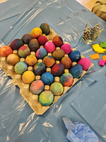 Bunte, dekorierte Eier in einem Karton auf einem blauen Tisch.
