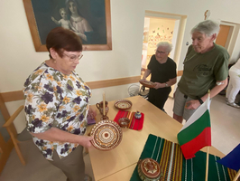 Drei Personen betrachten traditionelles Kunsthandwerk auf einem Tisch.
