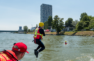 Rettungsschwimmer springt ins Wasser, um einer Person zu helfen.