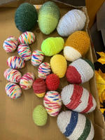 Bunte, gestrickte Ostereier in verschiedenen Größen und Formen auf einem Karton.
