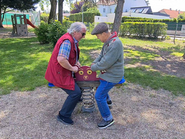 Zwei ältere Männer spielen auf einem Federspielgerät im Park.