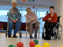 Drei Personen sitzen in einem Raum und schauen auf bunte Kegel.