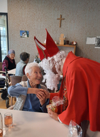 Eine ältere Frau erfreut sich am Besuch von einer festlich verkleideten Person.